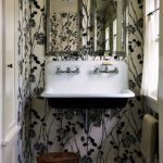 Charming powder room with a vintage double wall-mounted sink, botanical black-and-white wallpaper, and twin mirrors above.