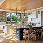 Spacious coastal kitchen with dual islands, wood ceiling, pendant lighting, natural light, and a mix of white and navy cabinetry.