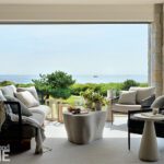 Open-air living room with plush seating, neutral furnishings, and panoramic views of the ocean and coastal landscape.