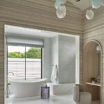 Spa-inspired primary bathroom with freestanding soaking tub, modern walk-in shower, and unique sculptural pendant lighting.