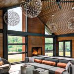 Cozy seating arrangement in front of a modern fireplace, highlighted by floor-to-ceiling windows and dramatic globe pendant lighting.