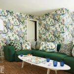 Colorful basement den with a green sectional sofa, botanical wallpaper, and playful accent pillows, creating a cozy family game space.