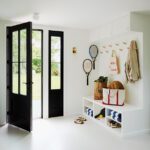 Functional mudroom with peg hooks, storage cubbies, and double black French doors leading to the backyard.