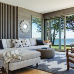 Bright living room with a sectional sofa, sliding glass doors, and a view of the ocean framed by trees