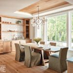 Light-filled dining area with large windows, natural wood cabinetry, and modern globe chandelier in a Cape Cod coastal home.