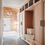 Custom wood mudroom with built-in storage, bench seating, and slate flooring leading into a shingled foyer.