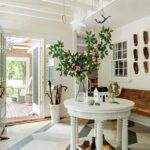 Bright Cape Cod entryway with a geometric painted floor, white round table, and whimsical décor including floral branches and hanging stars.