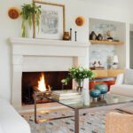 Contemporary living room with a stone fireplace, modern art, sculptural decor, and a geometric rug in a neutral palette.