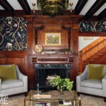 Sophisticated parlor with dark floral wallpaper, velvet pillows, a neutral sofa, and coffered wood ceilings.