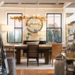 Sophisticated dining room setup inside Living Swell featuring a wood table, woven chairs, gold chandelier, and curated tabletop accessories.