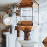 Detailed view of a handcrafted copper lantern with glass housing displayed on a white post at Nauset Lantern Shop.