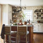 Country-style kitchen with a central island, floral patterned backsplash, open shelving, and rustic wood floors