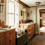 Sunlit bathroom with wood cabinetry, dual vanities, shiplap walls, and woven sconces flanking large mirrors