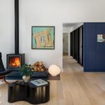 Sleek living area with a wood-burning stove, abstract art, sculptural coffee table, and bold navy cabinetry