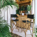 Coastal-style bamboo tiki bar with director’s chairs, grasscloth ceiling, and tropical greenery, creating a playful Palm Beach outdoor retreat.