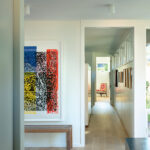 Bright hallway featuring natural wood flooring, clerestory windows, and vibrant modern art for a gallery-like effect.