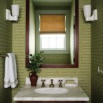 Bold powder room with green geometric wallpaper, marble vanity top, wood-framed mirror, and brass fixtures for a vintage touch.