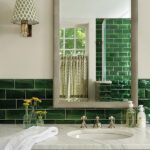 Elegant bathroom with emerald green subway tile, marble countertop, oversized mirror, and a mix of modern and vintage-inspired fixtures.