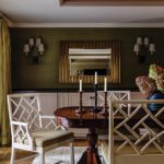 Elegant dining room with green grasscloth walls, cream chinoiserie chairs, and a round wood pedestal table beneath a tray ceiling.