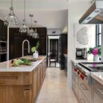 Warm, transitional-style kitchen featuring a rich wood island, pendant lighting, and stainless-steel appliances with a view toward a butler’s pantry.