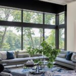 Spacious modern living room with panoramic windows, neutral furnishings, and scenic wooded views, designed by LDa Architecture.