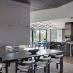 Open-concept living, dining, and kitchen area with modern finishes, statement lighting, and floor-to-ceiling windows.
