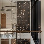 Striking modern staircase with cascading circular light fixtures and expansive windows in a contemporary architectural setting.