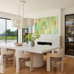 Contemporary dining room with a textured white table, sculptural lighting, and wine storage.