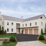 White modern coastal home with pitched roof and three-car garage.