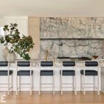 Luxurious kitchen with marble backsplash, waterfall island, and gold fixtures.