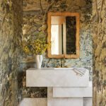 Artistic powder room with scenic wallpaper, marble sink, and gold accents.