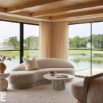Serene bedroom seating area with curved sofa and large windows overlooking the water.