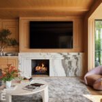Elegant sports lounge with marble fireplace, wood paneling, and cozy seating.