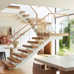 Floating staircase with glass railing in a sunlit modern interior.