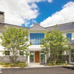 Grand coastal home with stone chimneys and white siding
