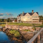 Grand waterfront home with stone foundation and expansive lawn