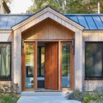 Contemporary home entry with natural wood door and vertical siding