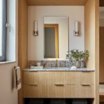 Wood‑wrapped vanity niche with granite countertop and wall sconces