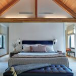 Vaulted bedroom with exposed beams and navy velvet headboard