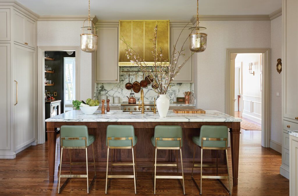 Elegant kitchen with marble island, brass range hood, and custom cabinetry by Erin Gates.
