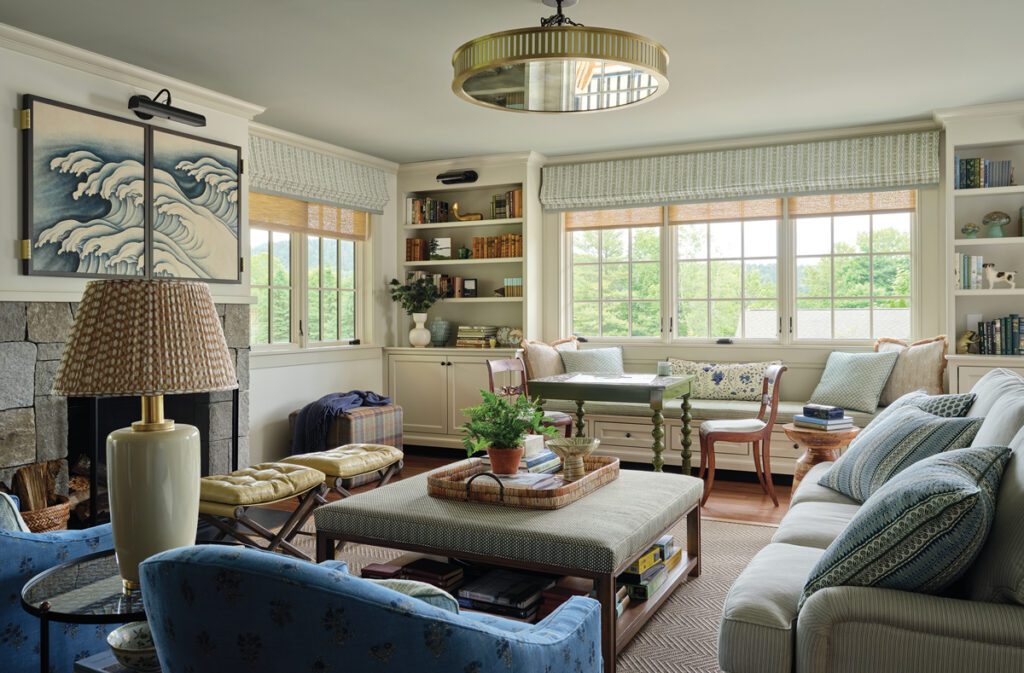 Transitional living room featuring built-in shelving, coastal wave artwork above the fireplace, and a mix of tailored and patterned seating.