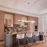 Contemporary kitchen with waterfall island, light wood cabinetry, and dramatic stone backsplash.