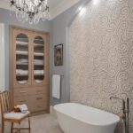 Elegant primary bathroom with a freestanding soaking tub, arched wallpaper feature wall, chandelier, and custom built-in linen cabinet.
