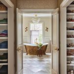 Luxurious bathroom with freestanding brass bathtub and patterned tile floor by Erin Gates.