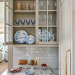 Built-in dish cabinet with blue-and-white ceramics and marble countertop styled by Erin Gates.