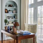 Refined home office with arched bookcase, wood desk, and French doors by Erin Gates.