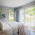 Light-filled bedroom with minimalist decor, glass doors, and garden views.