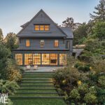 view of a traditional gray home with expansive windows and terraced garden.
