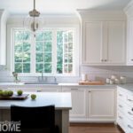 Sunlit kitchen with classic white cabinetry, large window, and subway tile backsplash
