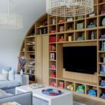 Stylish playroom with built-in arched shelving, a TV wall, and cozy seating in a neutral color palette.